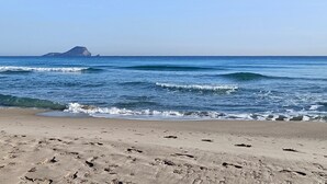 Une plage où l’on voit des empreintes dans le sable et où les vagues se rapprochent du rivage.