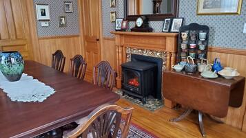 Un comedor con mesa de madera, sillas, chimenea y una estantería con adornos.