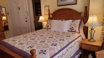 A neatly made bed with a patterned quilt, two bedside lamps, and a wooden headboard.