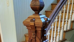 A wooden staircase with a handrail and a chair at the bottom. - The Lark & Loon Inn (Annapolis Royal)