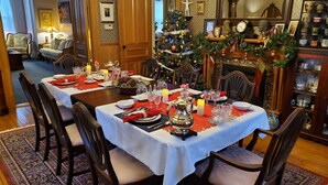 A dining area with a Christmas tree, wooden furniture, and a fireplace. - The Lark & Loon Inn (Annapolis Royal)