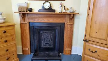 Una chimenea con un reloj encima, flanqueada por armarios de madera y un aparador.