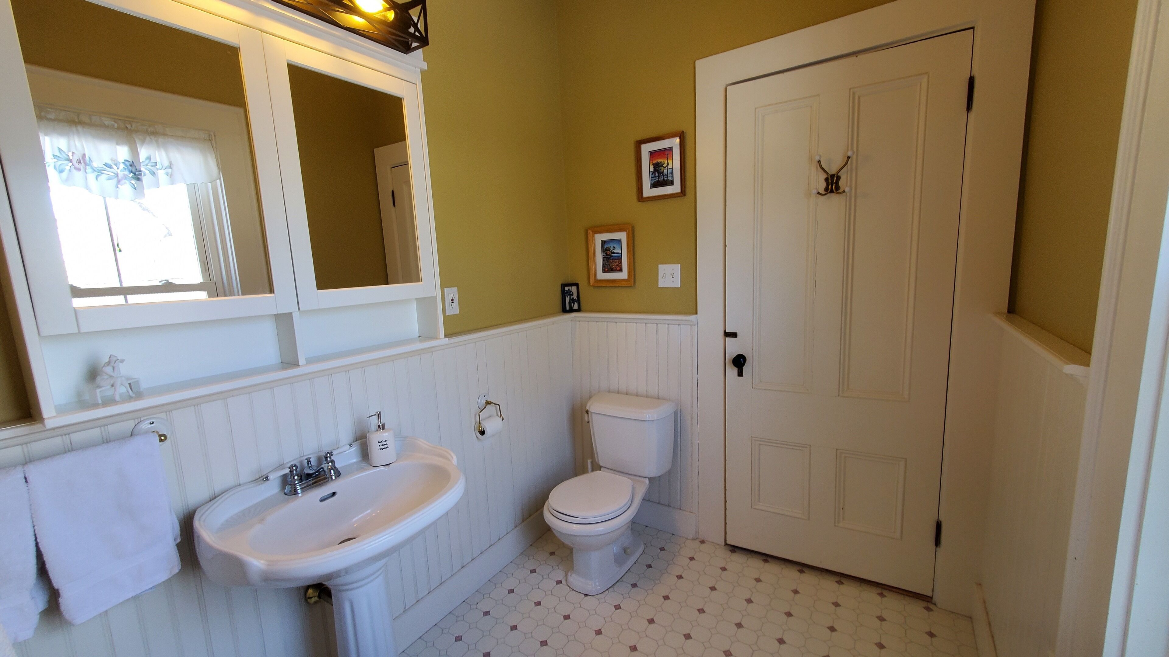 A bathroom with a white sink, toilet, and a door with a keyhole lock.