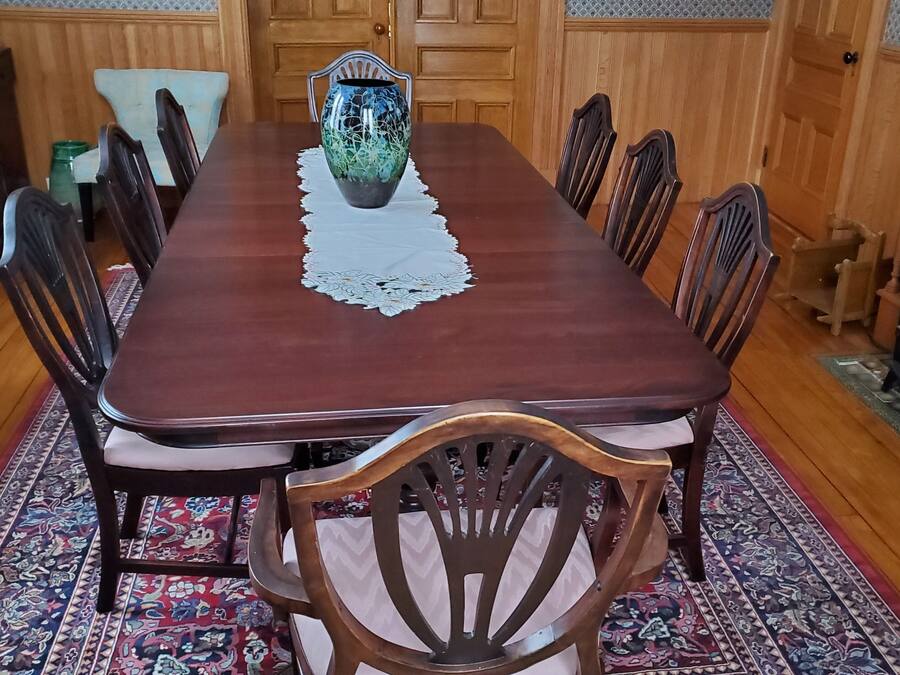 A dining room with a wooden table, chairs, a vase, and a fireplace.