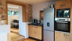 A modern kitchen with wooden cabinets, a built-in oven, and a refrigerator. - Comfortable apartment 300 m from the beach (Dinard)
