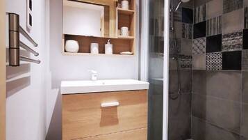 A modern bathroom with a wooden vanity, a glass shower enclosure, and a tiled shower wall.