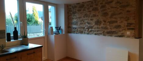 Una cocina con armarios de madera, pared de piedra y ventana con vistas al exterior.