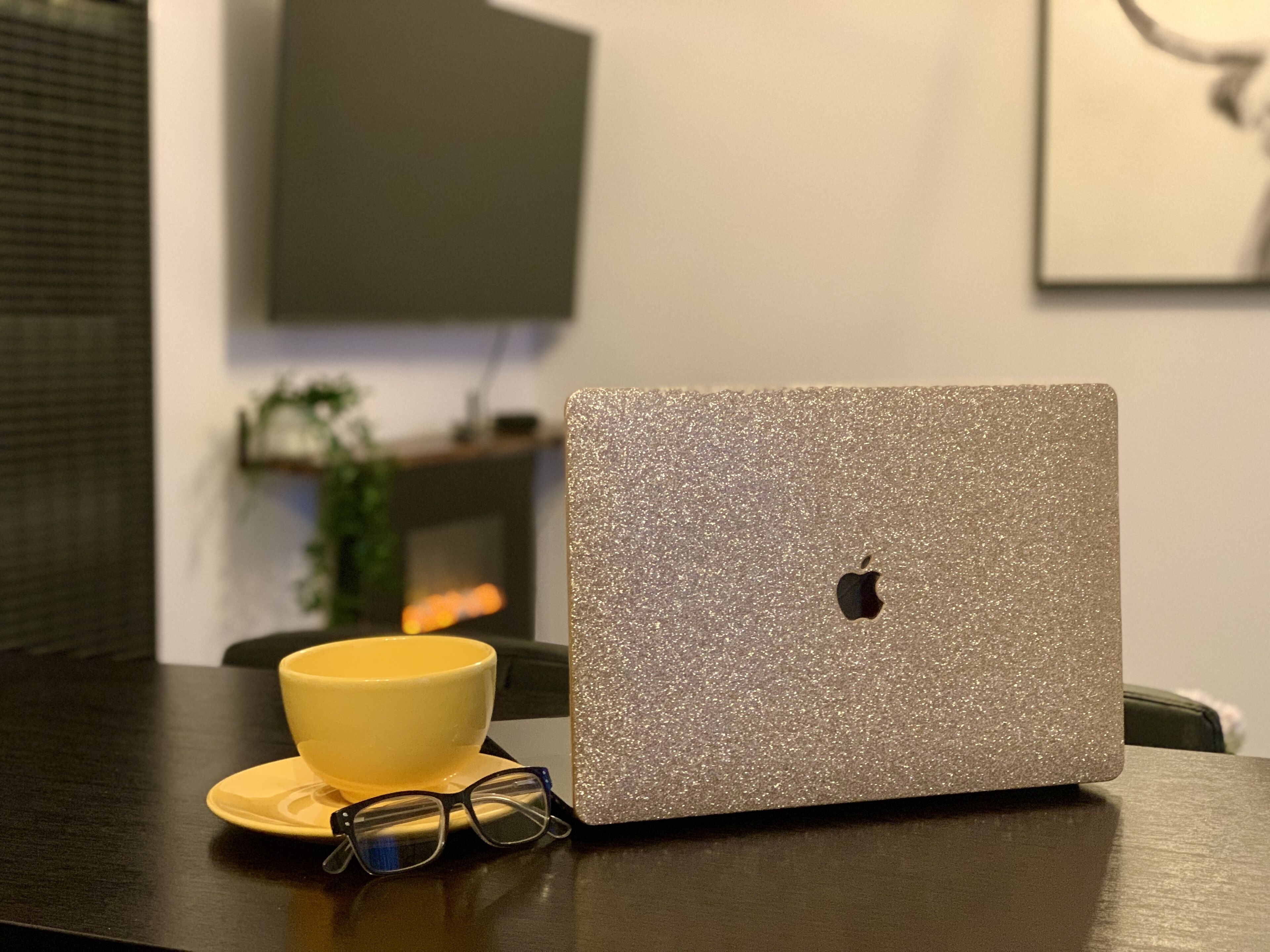 Ein Laptop mit glitzerndem silbernen Deckel auf einem dunklen Holztisch.