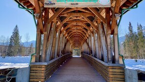 A wooden pedestrian bridge with a sign reading "Kicking Horse Pedestrian Bridge" and "Built in 2001". - Cozy Downtown Suite - Walking Distance to Restaurants & shops - Quiet Area (Golden)