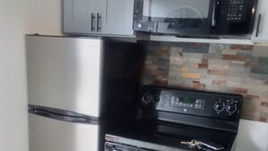 Eine kompakte Küche mit einem Edelstahlkühlschrank, einer Mikrowelle und einem Backofen.