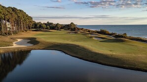 A golf course with bunkers and a water body, surrounded by trees and a view of the ocean. - Beach, beach, in historic Cape Charles. Lovely 2BR Apt. 1 Block from beach (Cape Charles)