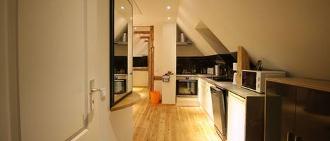 Eine moderne Küche mit Holzboden, Edelstahlgeräten und einem weißen Kühlschrank.