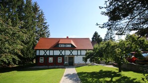A traditional half-timbered house with a red roof, a stone pathway leading to the entrance, and a well-maintained lawn. - Vacation apartment in a half-timbered house (Jonsdorf)