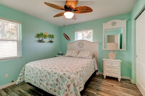 A bedroom with a bed, a nightstand, a dresser, a ceiling fan, and a window.