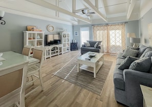 Relax in this spacious living room with a mounted TV, sofa, and dining area.