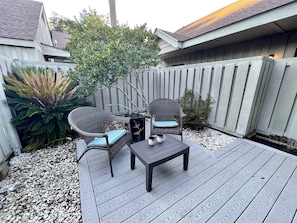 Relax and socialize in this serene outdoor space, featuring a table, two chairs, and lush greenery.