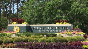 Schild für den Palmetto Dunes Oceanfront Resort mit einem angelegten Garten davor.