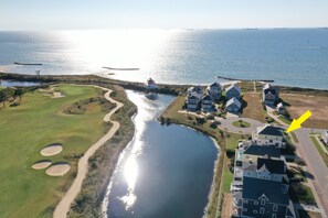 Stunning views of a well-maintained golf course and serene water body, surrounded by residential homes and a scenic bridge to the beach.