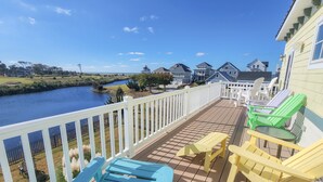 A deck with outdoor furniture overlooking a river and houses. - Gorgeous 4BR Home With Panoramic Sunsets & Walking Distance to Private Beach! (Cape Charles)