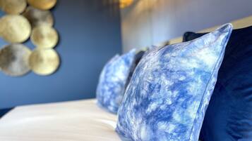 Una cama con sábana blanca y almohadas estampadas en azul.