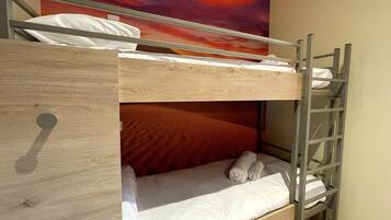 Een stapelbed met een houten frame, witte beddengoed en een ladder.