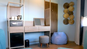A modern room with a built-in desk, a small stool, a bean bag, and a wall-mounted decorative item. - Hex Wildlife Hotel (Doncaster)