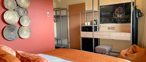 Una habitación de hotel moderna con cama, armario, televisor y un adorno en la pared.