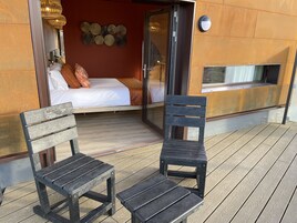Un dormitorio acogedor con una cama, un banco de madera y una silla en un piso de madera.