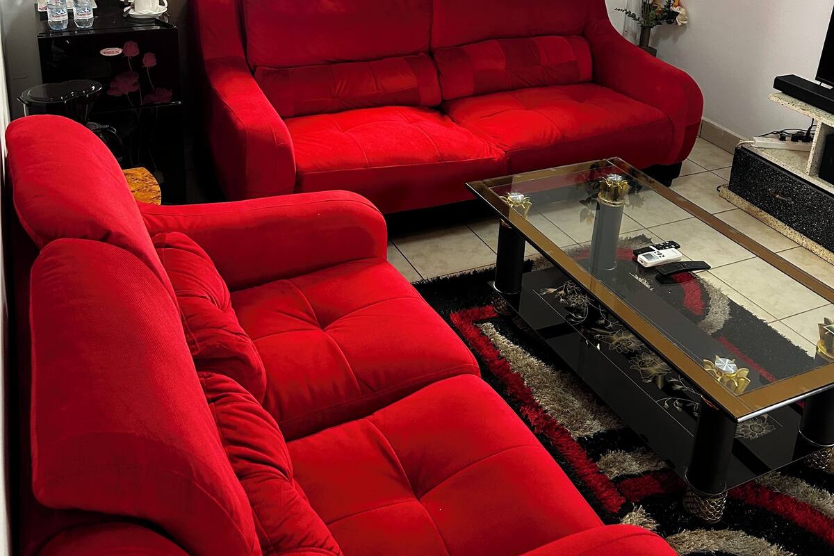 A living room with a red sofa, a glass coffee table, and a decorative vase.