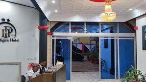 Het interieur van Hotel Prodiges, met een receptiebalie, een kroonluchter en uitzicht op het buitengebied.