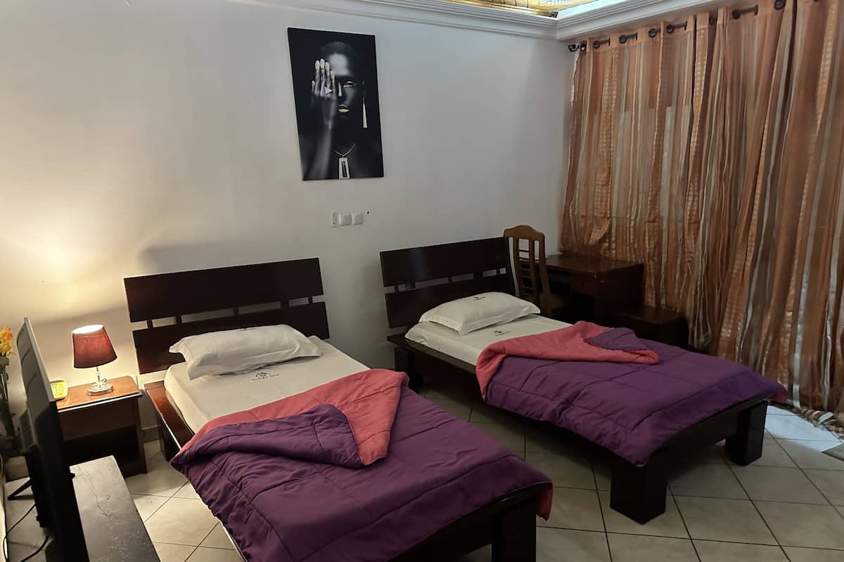 A room with two beds, a desk, a lamp, and a poster on the wall.