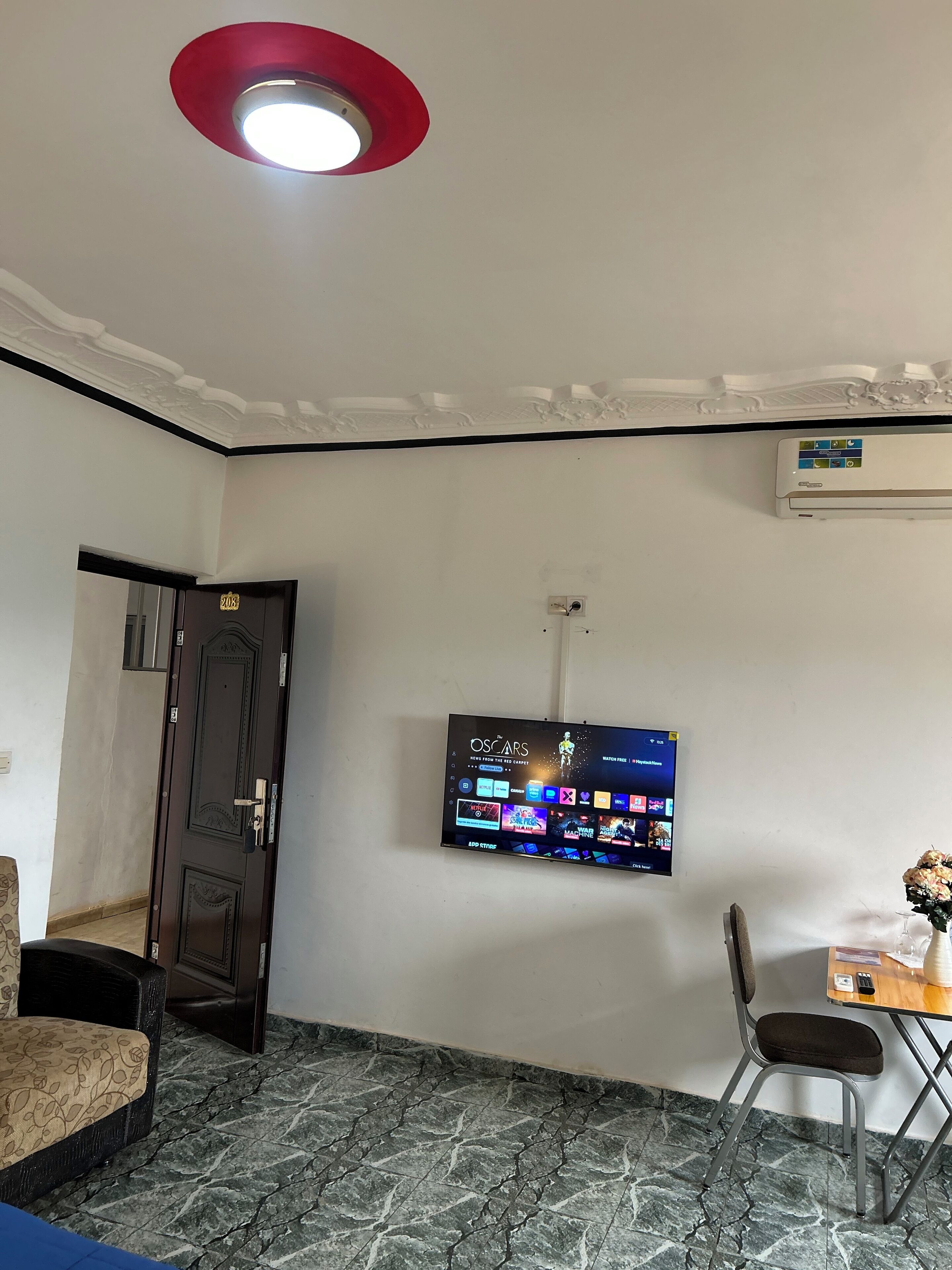 A room with a flat-screen TV mounted on the wall displaying the Oscars.