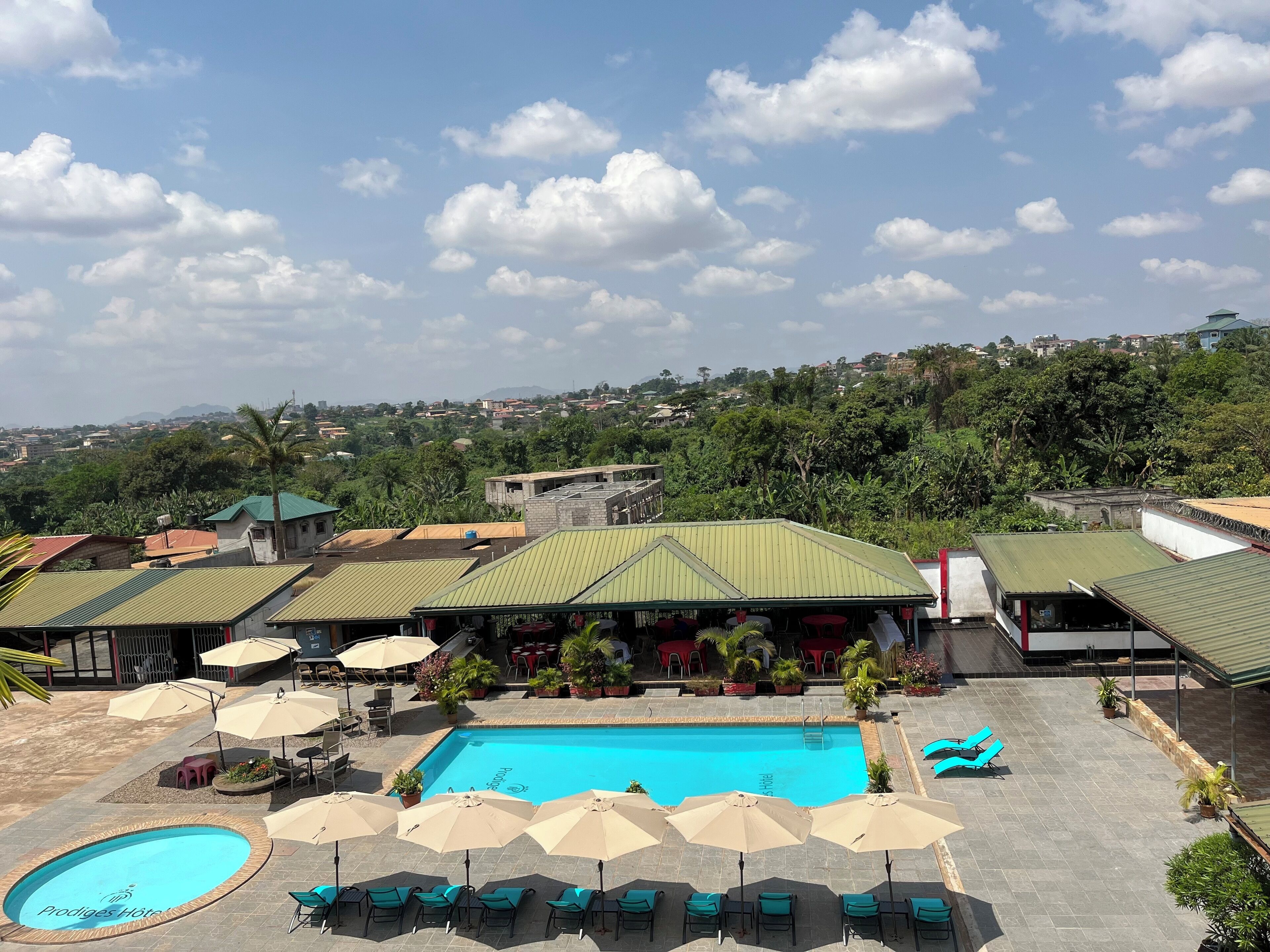 A hotel with a swimming pool, outdoor seating, and a view of the surrounding area.