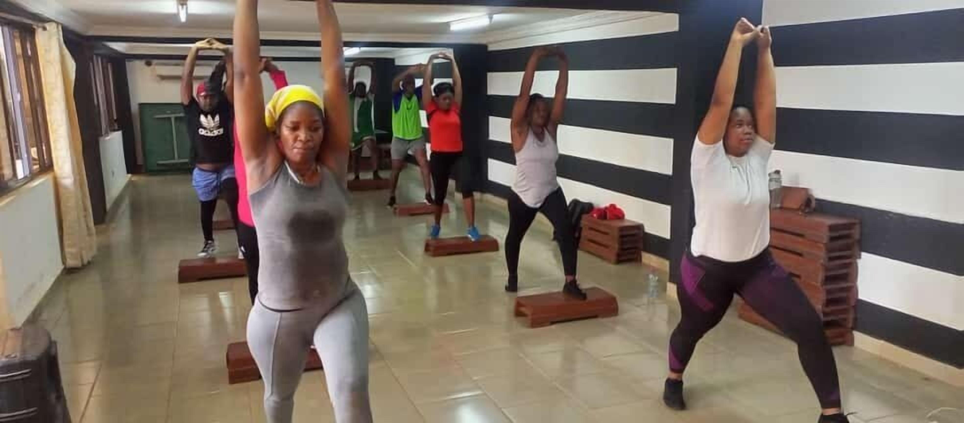 A group of people exercising in a room with a striped wall and wooden blocks.