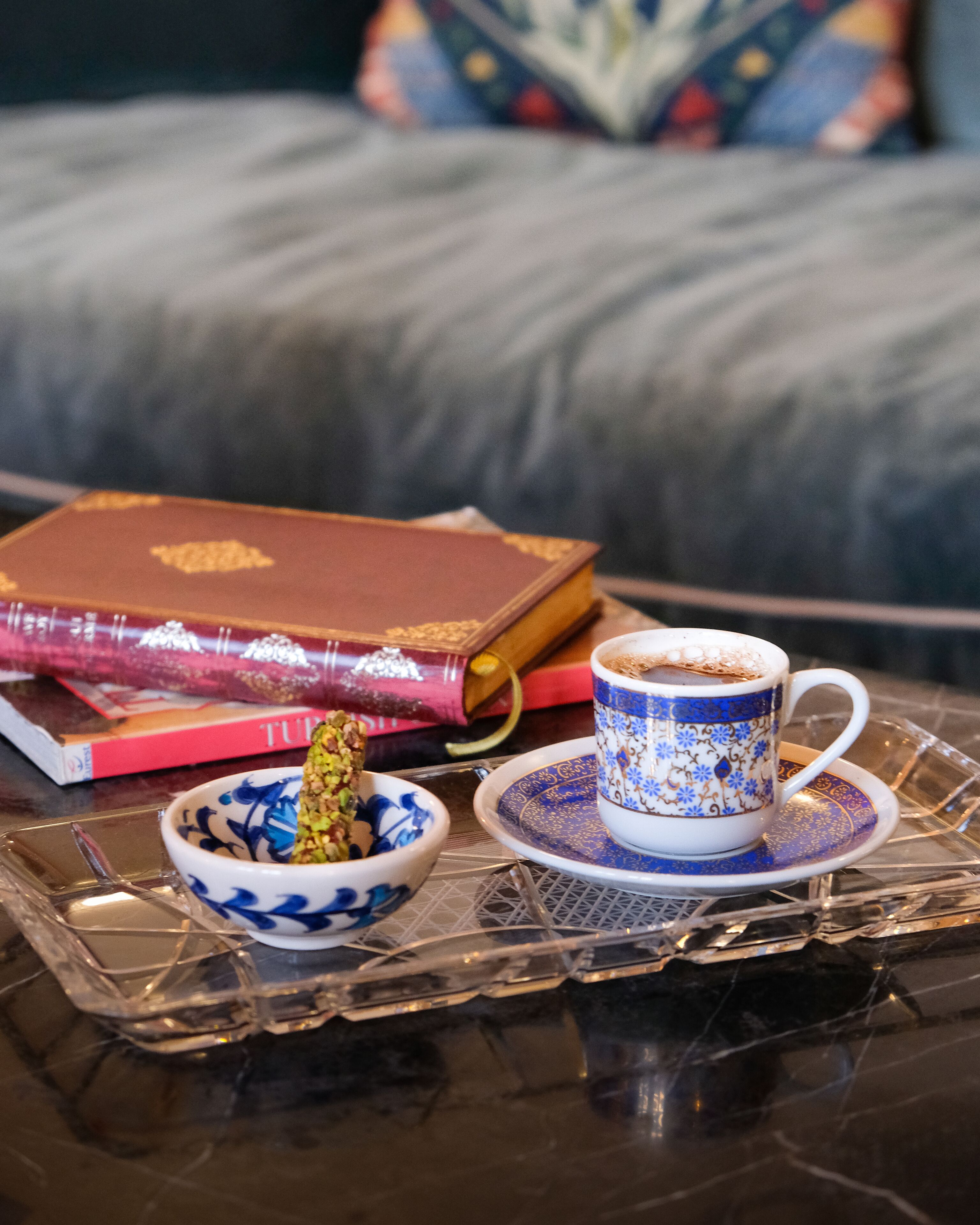 Una bandeja con una taza de café, un cuenco de frutos secos y un libro sobre una mesa.