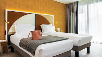 Ein Hotelzimmer mit einem großen Bett, einem Nachttisch, einer Lampe und einem Fenster mit Vorhängen.