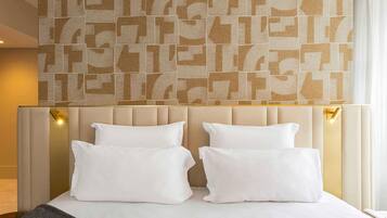 Une chambre d’hôtel avec un grand lit, une tête de lit dotée de panneaux de couleur claire et un mur au-dessus du lit orné d’un motif géométrique.