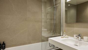 A modern bathroom with a glass-enclosed shower, a white sink, and a large mirror.