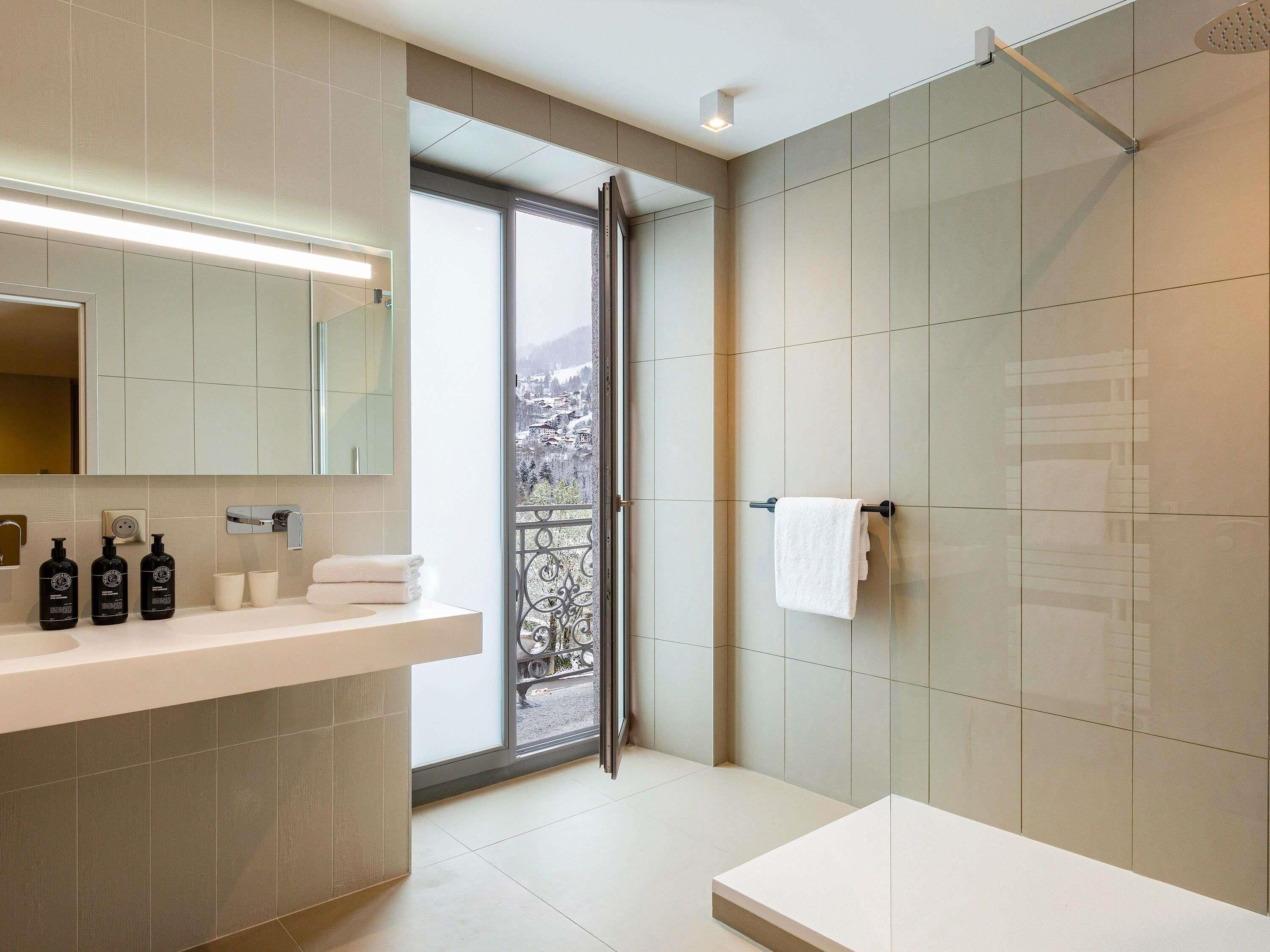 Un bagno moderno con uno specchio grande, un lavandino bianco e un box doccia.