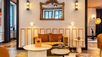 A room with a sofa, two round tables, a mirror, and wall sconces.