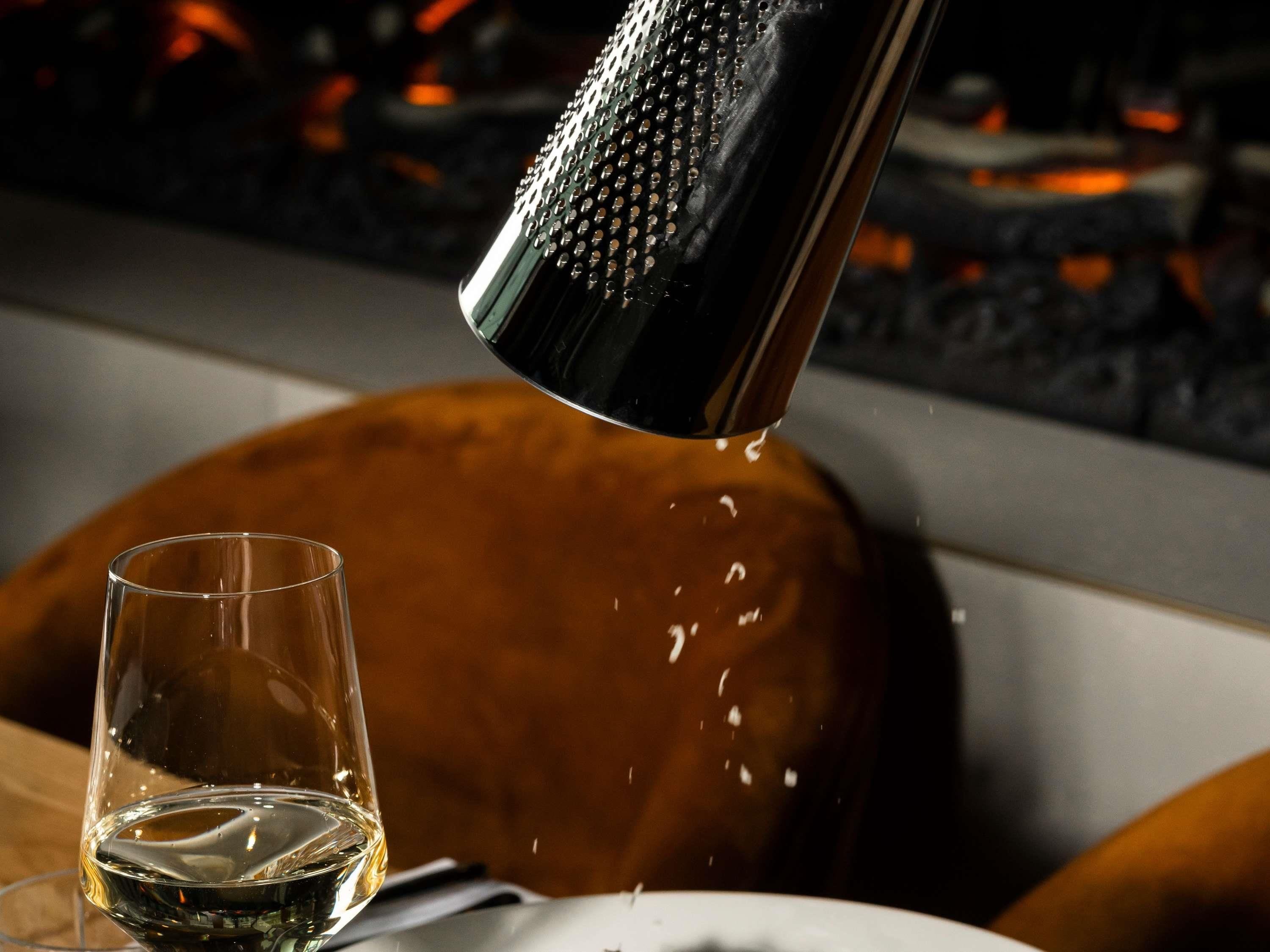 A bar setting with a glass of liquid being poured from a shaker.