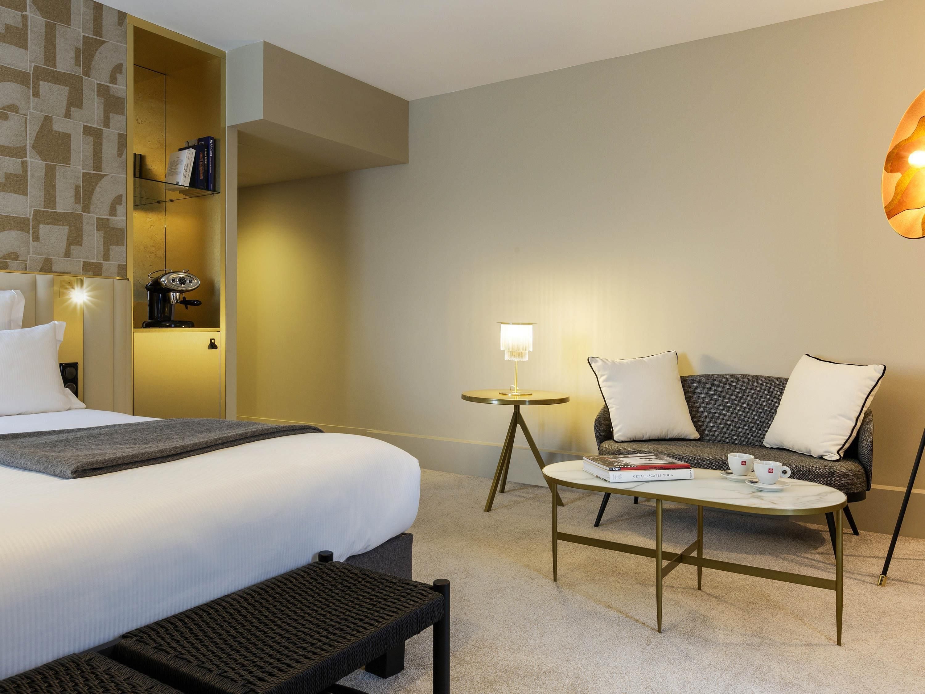 Une chambre d’hôtel avec un lit, un canapé, une petite table, une lampe et une table basse.