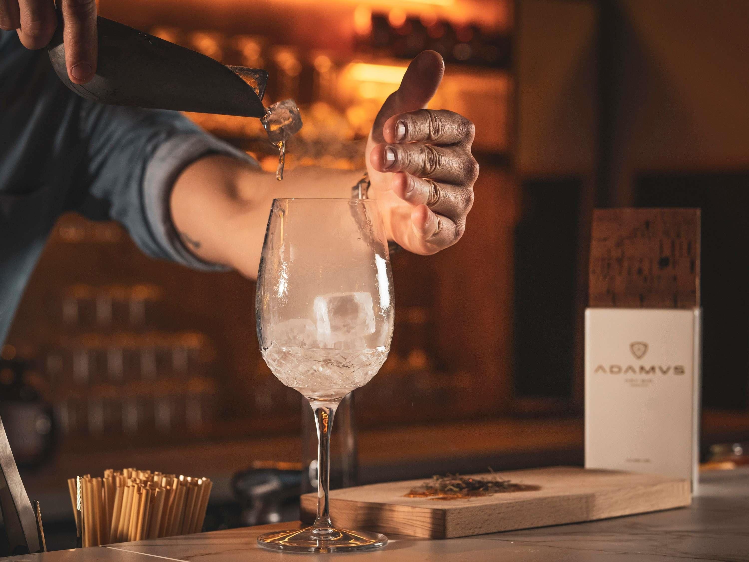 A bartender pouring a drink into a glass.