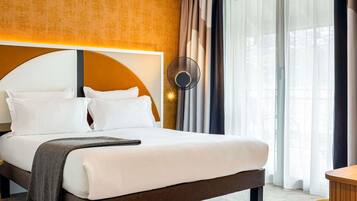 Une chambre d’hôtel avec un grand lit, une horloge murale ronde et une vue sur l’extérieur à travers de fines rideaux.