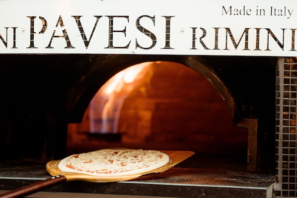 Un horno de pizza con una pizza sobre una tabla de madera.