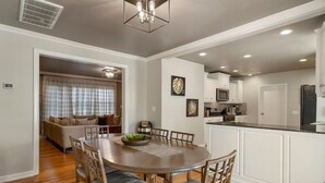 A modern kitchen with white cabinetry, a central island, and a dining area with a round table and chairs.