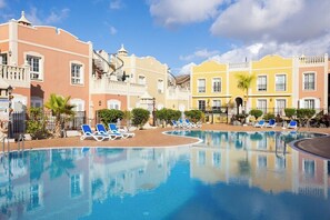 A swimming pool with blue lounge chairs, surrounded by buildings with balconies and windows. - Home2Book Palm Beach & Relax (Palm-Mar)