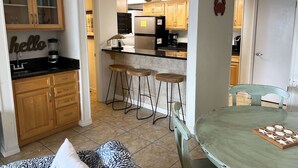 Une cuisine compacte avec des meubles en bois, un plan de travail noir et un coin bar avec des tabourets.