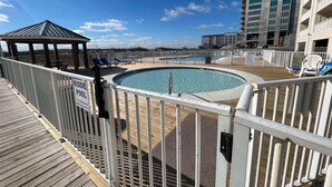 Un espace piscine comprenant une pataugeoire, des chaises longues et un kiosque.