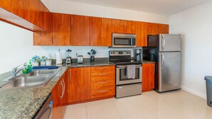 A modern kitchen with wooden cabinets, stainless steel appliances, and granite countertops.